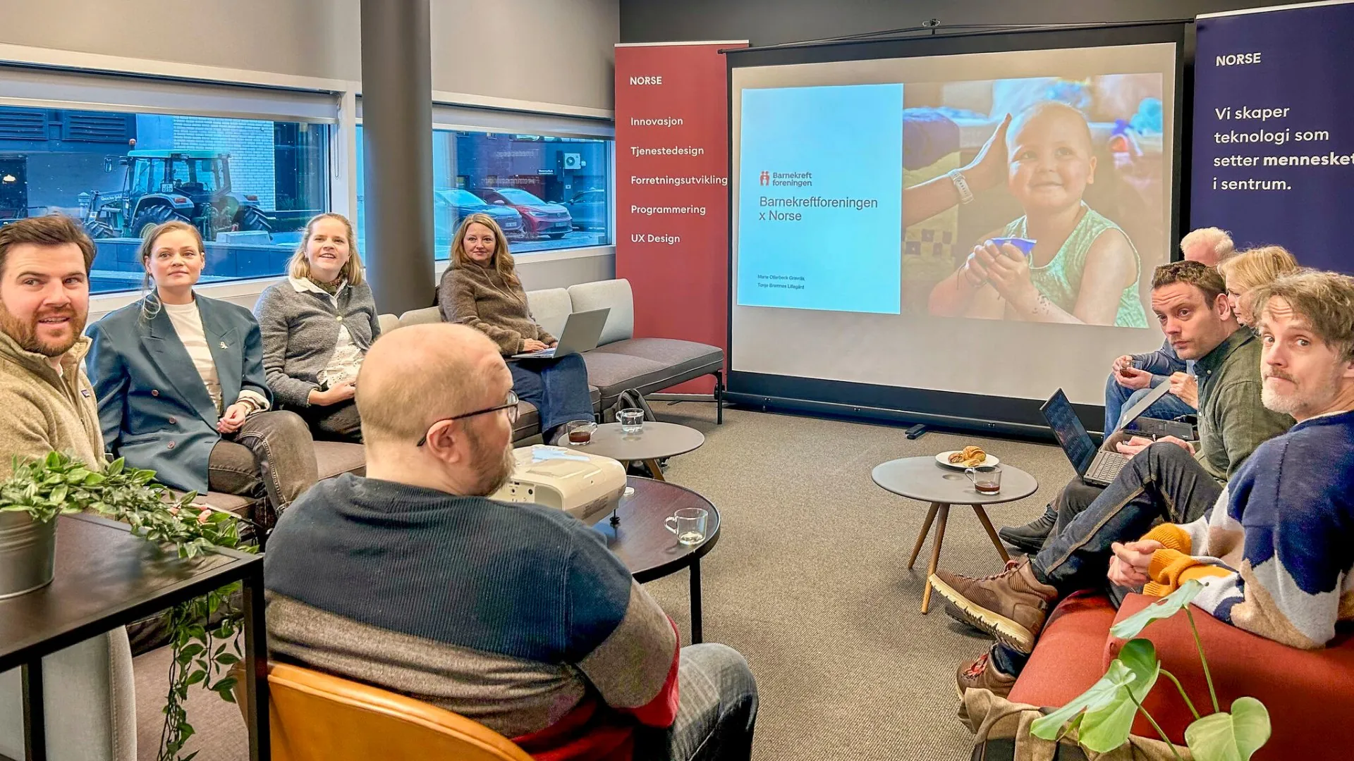 Workshop hos Norse Digital med deltakere samlet rundt en presentasjon om Barnekreftforeningen x Norse.